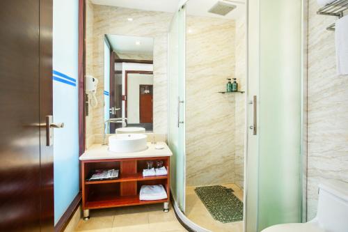 a bathroom with a sink and a shower with a mirror at Shengyi Holiday Villa Hotel in Sanya