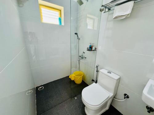 a white bathroom with a toilet and a sink at The Jade Highlands Mountain View 2 bhk Villa in Kodaikānāl