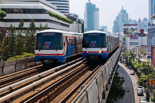 バンコクにある108 Quiet and Cozy apartment w/free Wi-Fiの2本の列車が街路に出ている