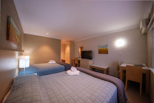 Habitación de hotel con 2 camas, mesa y cocina en Imperial Motel, en Bowral