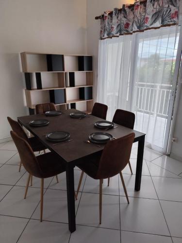 a dining room table with chairs in a room at La pause marie-galantaise in Capesterre