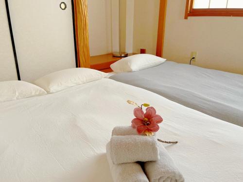 two beds with towels and a flower on them at 福嘉の九条 in Osaka