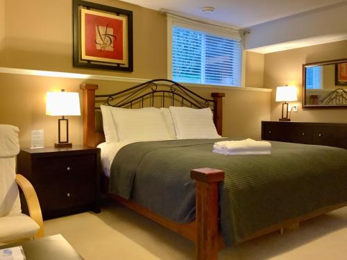 a bedroom with a large bed with two lamps and a chair at NeckPoint Treasure BnB in Nanaimo