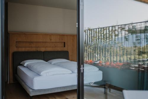 een bed met witte kussens in een kamer bij Stollhof - New 2024 in Lagundo