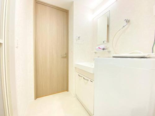 uma casa de banho branca com um lavatório e um espelho em アネックス日本橋東401 em Osaka