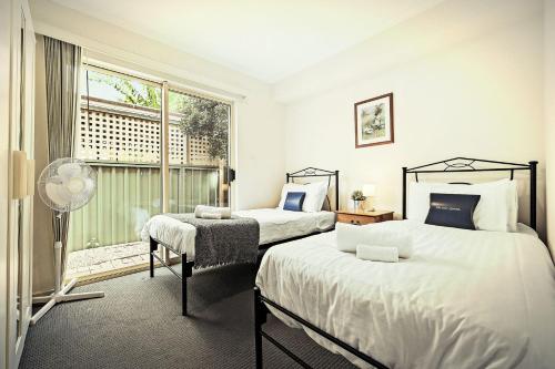 2 camas en un dormitorio con ventana y ventilador en 2 BR Apartment in Melbourne Street - North Adelaide en Adelaida