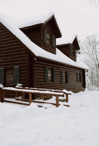 a log cabin in the snow with a bench in front at the log cabin in Deerwood