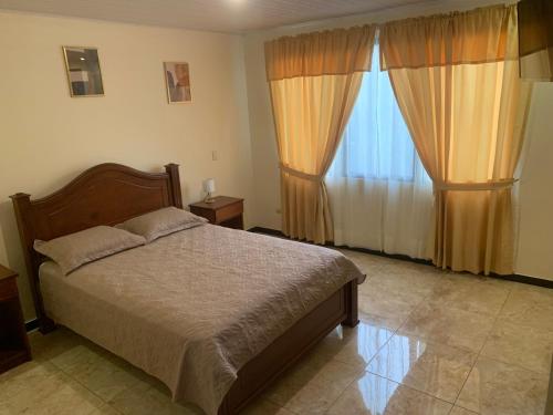 een slaapkamer met een bed en een groot raam bij El Tambor B1 in Alajuela