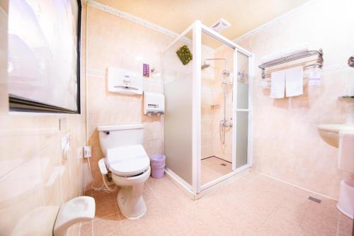a bathroom with a shower and a toilet and a sink at Wen Sha Bao Motel-Xinying in Xinying