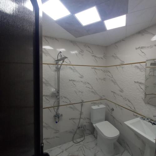 a white bathroom with a toilet and a sink at Lahij Rashad Ismayilov Hotel in Lahıc
