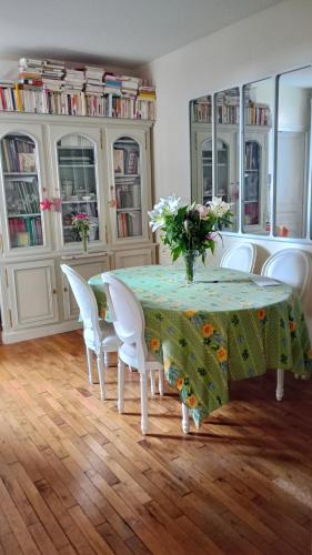 - une table avec des chaises blanches et un vase de fleurs dans l'établissement Le havre de paix, à Paris