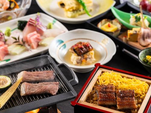 einen Tisch mit Speisen und Fleisch in der Unterkunft KAMENOI HOTEL Yanagawa in Yanagawa