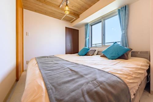 a bedroom with a large bed with blue pillows at Nakajima Park Hotel AMS tower Nakajima 18F 1801 in Sapporo