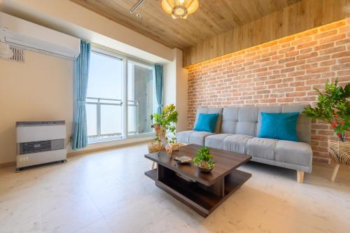 a living room with a couch and a brick wall at Nakajima Park Hotel AMS tower Nakajima 18F 1801 in Sapporo