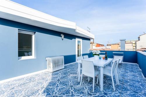 un patio con una mesa blanca y sillas en una pared azul en La Bella Vita - La Terrazza, en Sottomarina