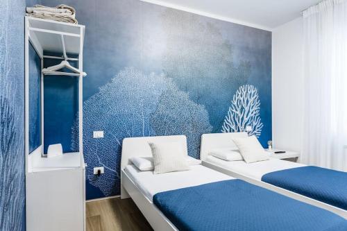 una camera con due letti e una parete blu di La Bella Vita - La Terrazza a Sottomarina