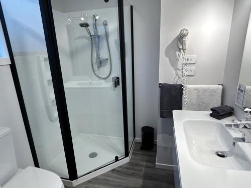 a bathroom with a shower and a sink at Shelby Motor Lodge in Invercargill