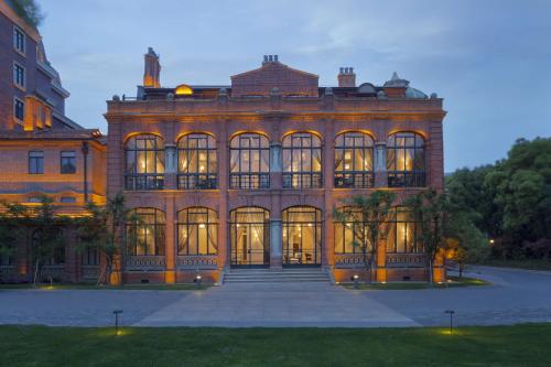 a large brick building with its lights on at InterContinental Shanghai Ruijin by IHG - Downtown Historic Iconic Garden Hotel in Shanghai