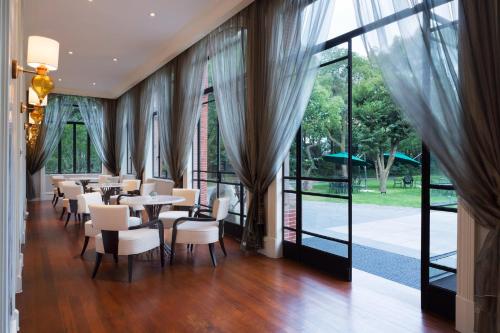 a dining room with tables and chairs and large windows at InterContinental Shanghai Ruijin by IHG - Downtown Historic Iconic Garden Hotel in Shanghai