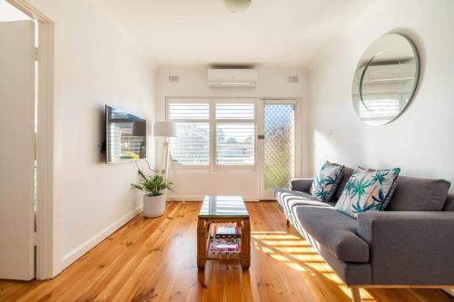 a living room with a couch and a table at Sams Henley Beach Garden Unit in Henley Beach