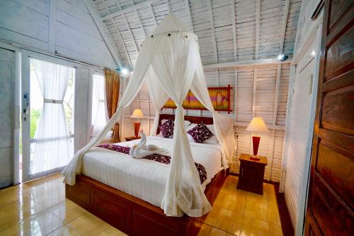 a bedroom with a bed with a mosquito net at Hotra Hill Cottage in Nusa Penida