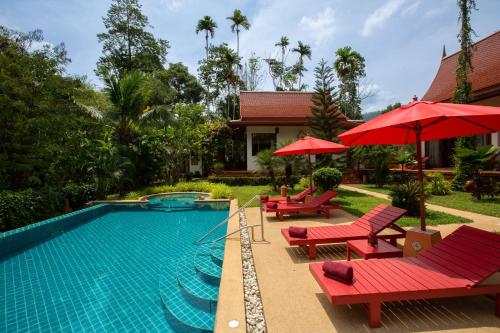 una piscina con sedie rosse e ombrelloni accanto a una casa di Villa Tropical Bliss Luxury Estate a Nathon Bay