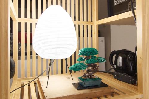 a lamp with a small tree in a room at Saku House Jujo in Tokyo
