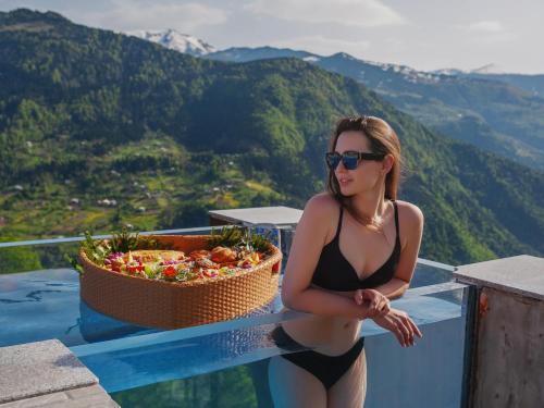 a woman in a bikini sitting on a ledge with a basket of flowers at Nika Hotel and Club in Chʼanchʼkhalo