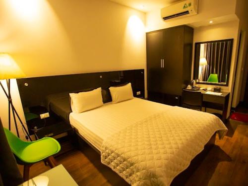 a hotel room with a bed and a green chair at Ánh Hồng Hottel in Hanoi