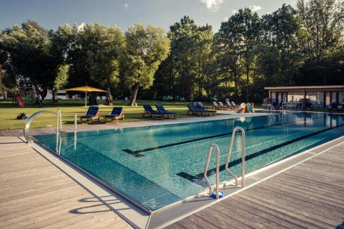a swimming pool with blue chairs and a wooden deck at Unikátní Chalet 6 vířivka & bazén in České Budějovice