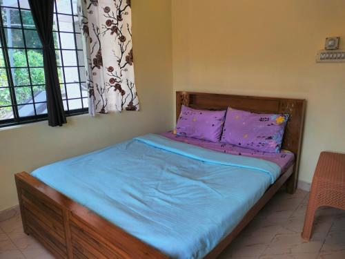 Un dormitorio con una cama con sábanas y ventanas púrpuras. en White bungalow, en Madikeri