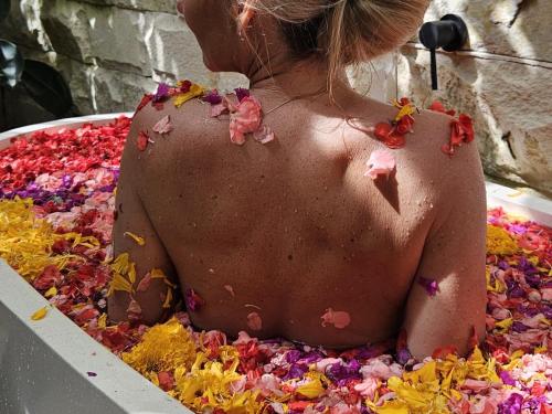 a woman sitting in a bath tub covered in confetti at ONAYA Bali Resort - Adults Only in Uluwatu