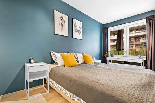 1 dormitorio con paredes azules y 1 cama con almohadas amarillas en New Apartment in Helsfyr Oslo, Near central Oslo, en Oslo