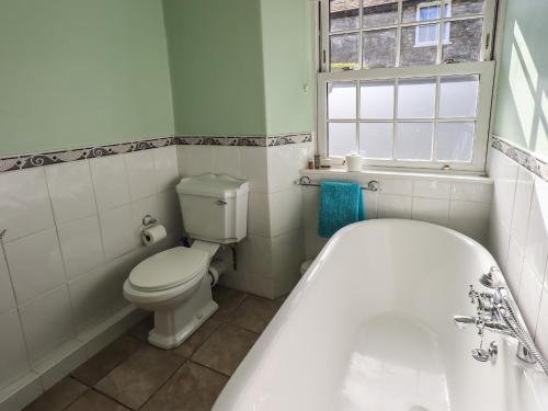 a bathroom with a white tub and a toilet at Tizzie Whizie Cottage in Windermere