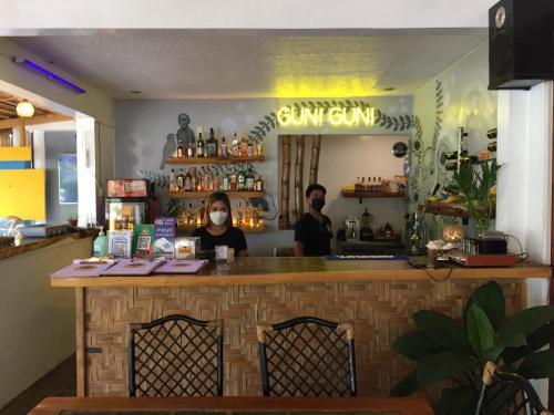 two people wearing face masks standing at a bar at GUNI GUNI HOSTEL in Puerto Princesa City