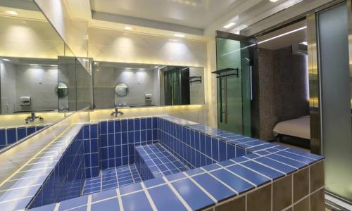 uma casa de banho com 2 espelhos e uma banheira de azulejos azuis em Hotel Eat Dot Com Alpeuseu Oncheon em Ulsan