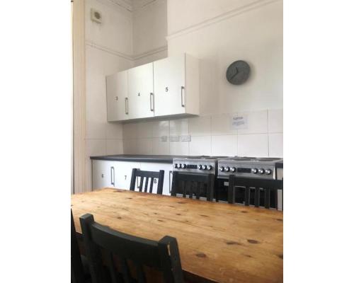 eine Küche mit einem Holztisch und eine Küche mit weißen Schränken in der Unterkunft St Paul's Road Townhouse by Clifton Short Lets in Bristol