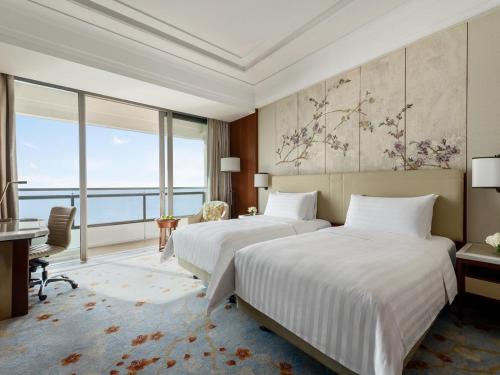 two beds in a room with a large window at Shangri-La Qinhuangdao in Qinhuangdao