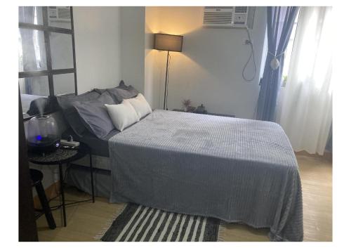 een slaapkamer met een bed, een tafel en een lamp bij Boheme Condotel at Trees Residences Studio2 in Manilla