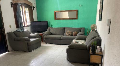 una sala de estar con 2 sofás y una pared verde en Casa lina, en Puerto Escondido