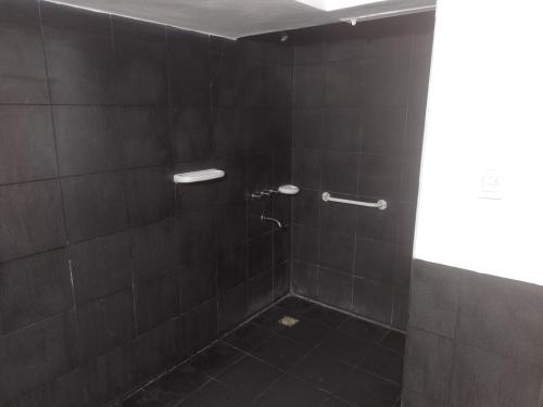 a bathroom with a shower with black tiles at Hotel Hualum in Villa Dolores