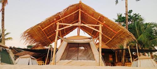 ein Zelt mit Strohdach am Strand in der Unterkunft Amwani Sunset Colours Camping Site in San Vicente