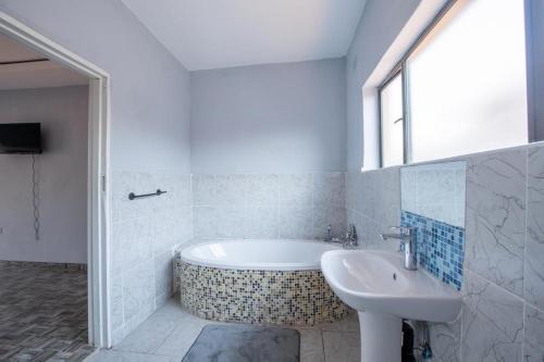 維多利亞瀑布的住宿－The Crescent Victoria Falls，白色的浴室设有浴缸和水槽。