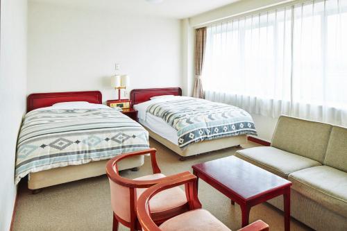uma sala de estar com 2 camas, um sofá e uma mesa em 砂川パークホテル em Sunagawa