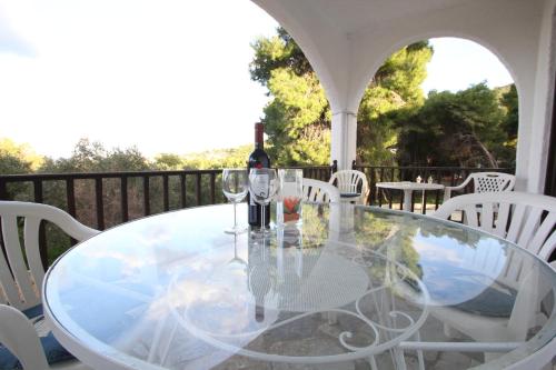 uma mesa de vidro com uma garrafa de vinho e copos em Attainable Heaven by Frangki em Vathí