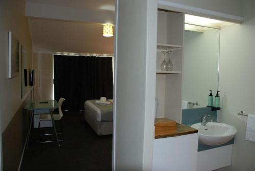 un bagno con lavandino e un letto in una camera di VR Auckland Airport ad Auckland