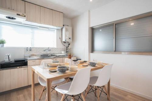 a kitchen with a wooden table and white chairs at 旅家 Kanzakigawa in Osaka