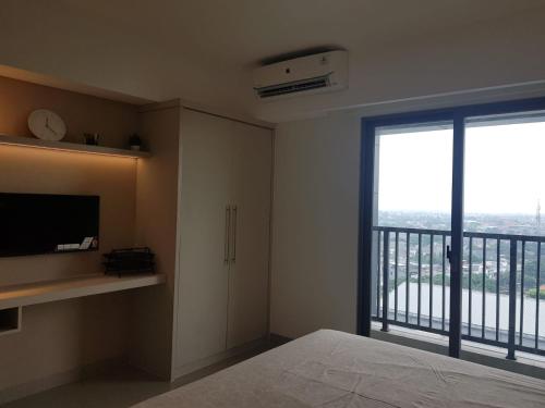 - une chambre avec un lit et une grande fenêtre dans l'établissement Apartment Embarcardero Bintaro 1BR, à Jombang