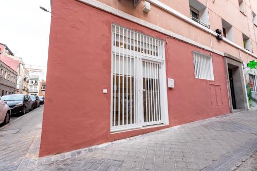 ein rotes Gebäude mit weißen Türen auf einer Straße in der Unterkunft Madrid, Centro, Cuatro caminos A in Madrid
