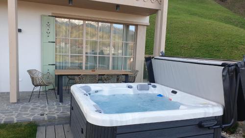 a jacuzzi tub on a patio with a table at Eny Guesthouse in Moieciu de Jos